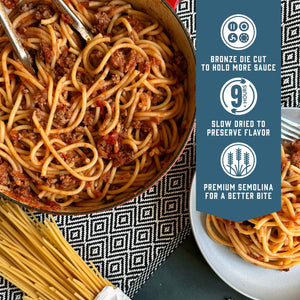 Prepared Sfoglini Bucatini pasta with meat sauce in a pot with a serving of pasta on a dish. With product feature icons and text - Bronze die cut to hold more sauce. Slow dried to preserve flavor. Premium semolina for a better bite.