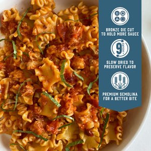 Prepared Sfoglini Reginetti pasta with red sauce on a dish. With product feature icons and text - Bronze die cut to hold more sauce. Slow dried to preserve flavor. Premium semolina for a better bite.