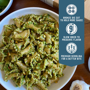 Prepared Sfoglini Whole Grain Rye Trumpets pasta with green pesto on a dish. With product feature icons and text - Bronze die cut to hold more sauce. Slow dried to preserve flavor. Premium semolina for a better bite.
