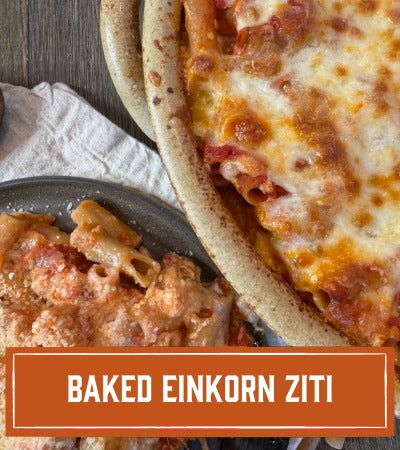 Baked Einkorn Ziti dish with a text overlay on a wooden surface