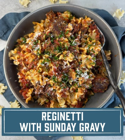 Sfoglini Reginetti with short ribs, classic meatballs, and Italian sausage in a gray bowl on a blue napkin. with text "Reginetti with Sunday Gravy"