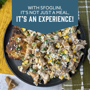 A plated pasta dish with Rye Trumpets, chicken, corn, and crumbled cheese on a dark plate, set on a yellow and green tablecloth. With text  - WITH SFOGLINI, IT'S NOT JUST A MEAL, IT'S AN EXPERIENCE!