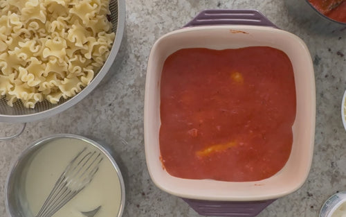 Video of lasagna being layered with Sfoglini Reginetti, red sauce, cream sauce, and cheese. With the text "With Sfoglini, it's not just a meal, it's an experience!"